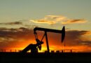 Oil pump jack silhouette against a vibrant sunset sky