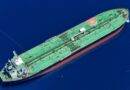 Aerial view of a large green oil tanker sailing in deep blue ocean water