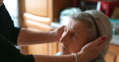 A caregiver gently assisting a senior woman at home
