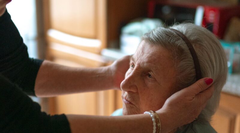 A caregiver gently assisting a senior woman at home