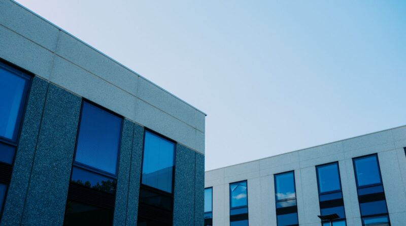 Modern commercial office buildings with reflective glass windows under a clear blue sky