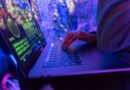 Close-up of hands typing on a laptop displaying cybersecurity graphics in purple light
