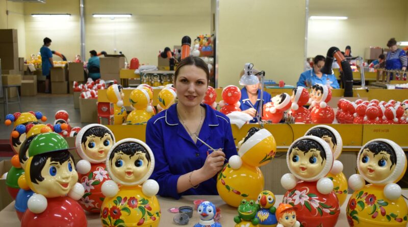 A worker painting colorful toys in a toy factory